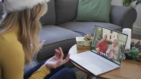 senior caucasian parents and adult daughter having christmas laptop video call, slow motion