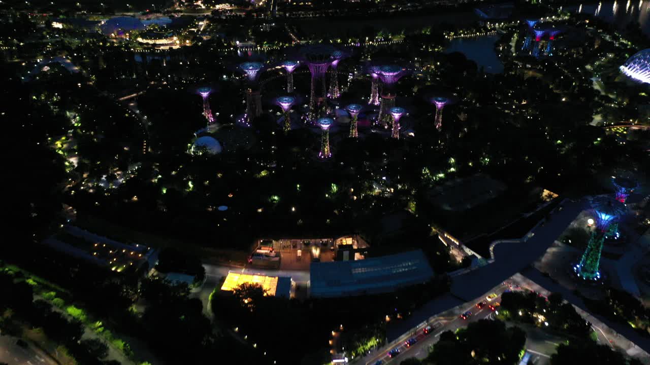 Night aerial footage of the Gardens By The Bay and Marina Bay Sands Tower in Singapore