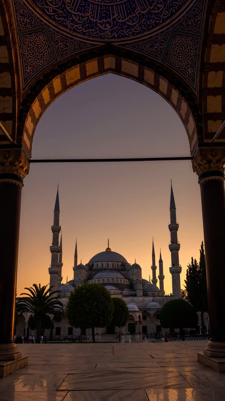 Video con angolazione dal basso di una maestosa moschea all'alba, che mette in risalto le sue cupole elaborate