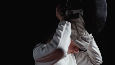 a fencer wearing a white uniform and mask prepares for a match