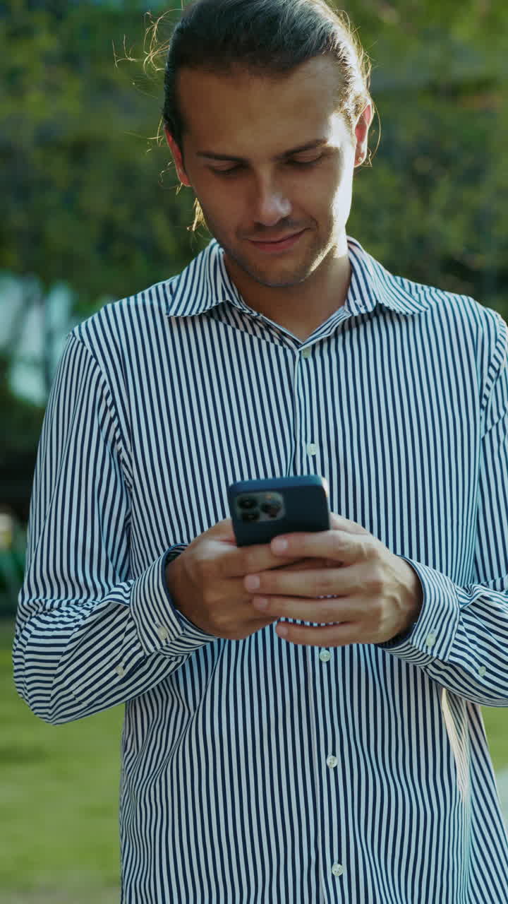 Giovane uomo intento a usare lo smartphone all'aperto