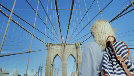 a tourist with a flag of america and a backpacker is walking along the famous brooklyn bridge in new