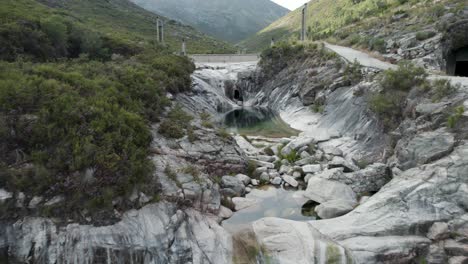 Aerial-backwards-view-of-stream-in-impressive-bed-with-boulders