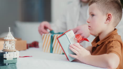 dad watches son wrap presents