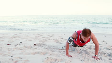 fit man doing push ups on the beach