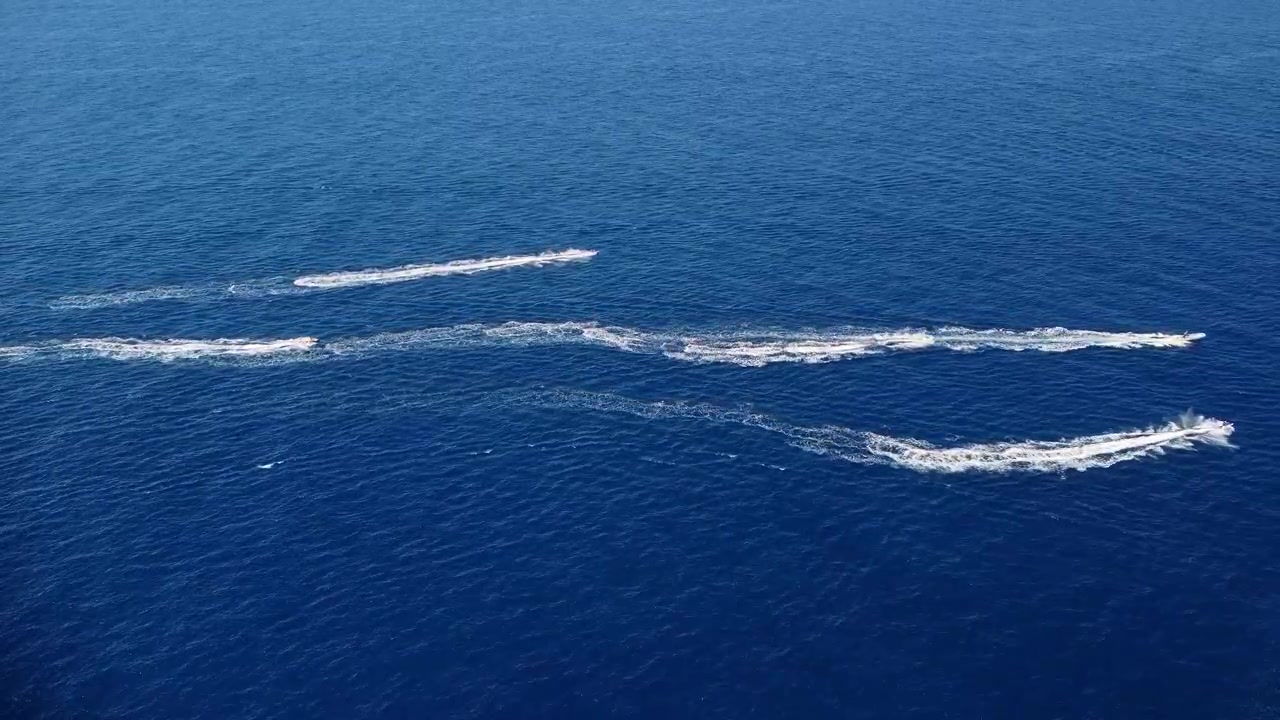 Motoscafi che sfrecciano veloci uno accanto all'altro in acque marine azzurre.