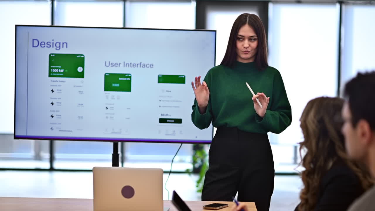 Female worker leading business meeting in an office, discussing business affairs with other workers using a big display with info. Slow motion
