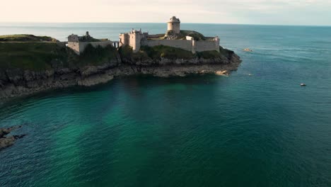 epic drone shot around Fort La Latte Castle, Chateau de la Roche Guyon, on the Brittany coast with Cap Frehel in the background, Cotes d&#039;Armor, France