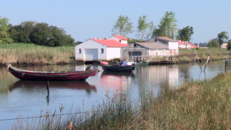 Ria-de-Ovar-in-its-great-natural-beauty,-with-two-traditional-fishing-boats,-built-in-wood,-with-the-houses-in-the-background