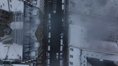 Vista-Aérea-De-Pájaros-Arriba-Abajo-Vista-Panorámica-Sobre-La-Conducción-De-Automóviles-En-La-Calle-En-La-Ciudad-De-Invierno.-Techos-Nevados-De-Edificios-Alrededor.-Berlín,-Alemania