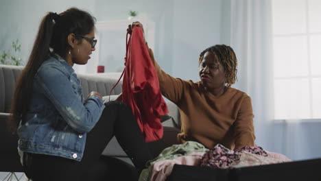 indian and african american women choose clothes for trip