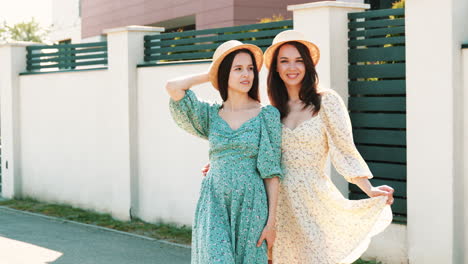 two women in floral dresses and straw hats