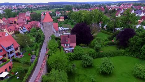 Luftaufnahme-über-Die-Stadtmauer-Mit-Türmen-Rechts-Ist-Ein-Grüner-Park-Und-Links-Die-Altstadt-Und-Die-Häuser-Mit-Roten-Dächern