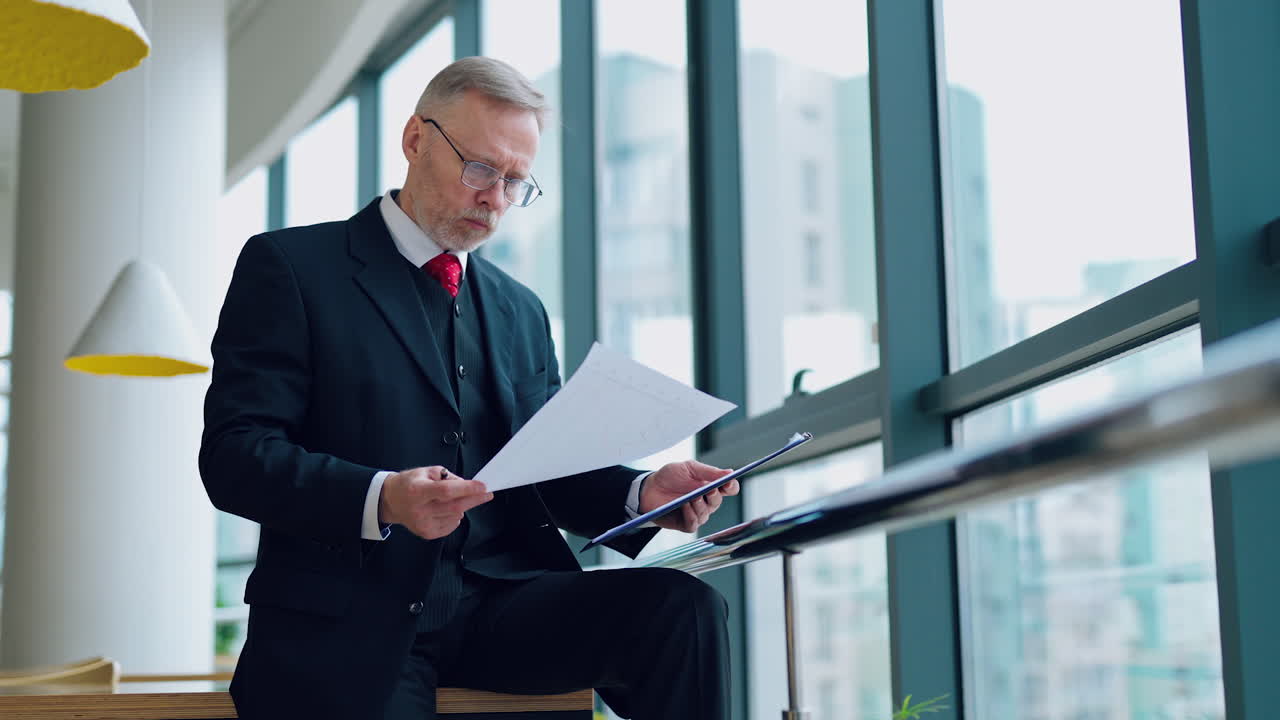 Portrait of mature man in cafe. Mature businessman sitting at coffee shop with documents