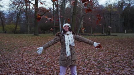 Mujer-Feliz-Tirando-Hojas-De-Otoño-En-Un-Parque