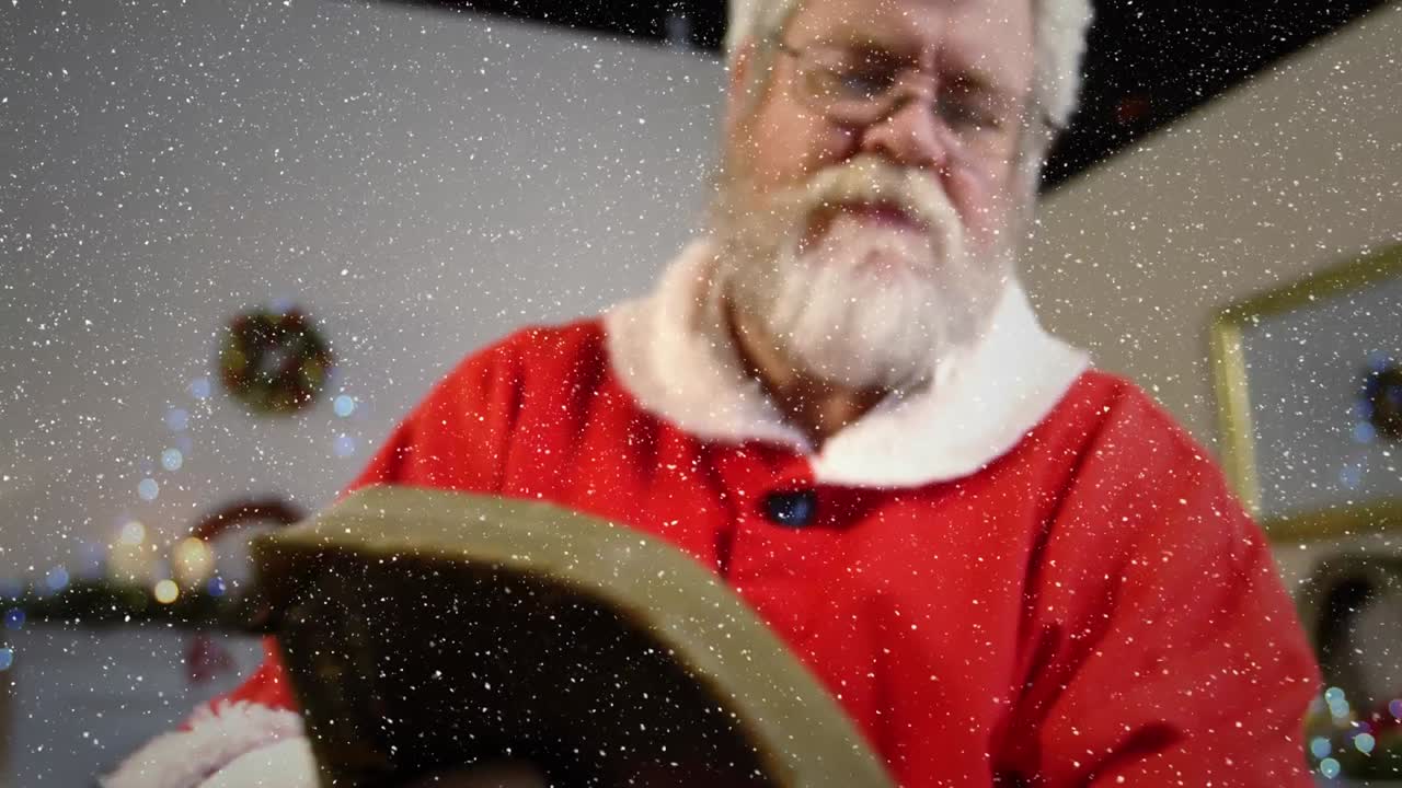composición de video con nieve cayendo sobre cámara lenta santa hojeando el libro
