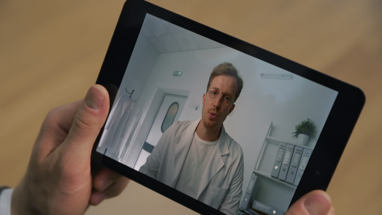 Um profissional da saúde falando por tela de tablet on-line em close-up no escritório. Homem segurando tablet