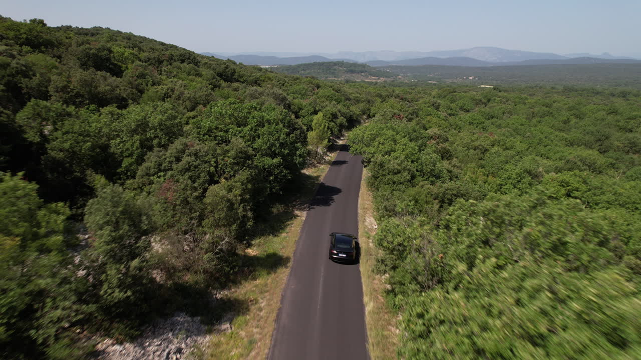 Following an electric car on a road surrounded by forest south of France
