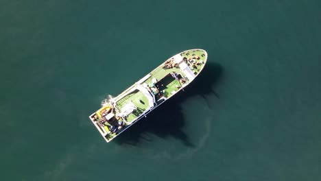 marine research motor vessel as seen from above casting a shadow on the ocean