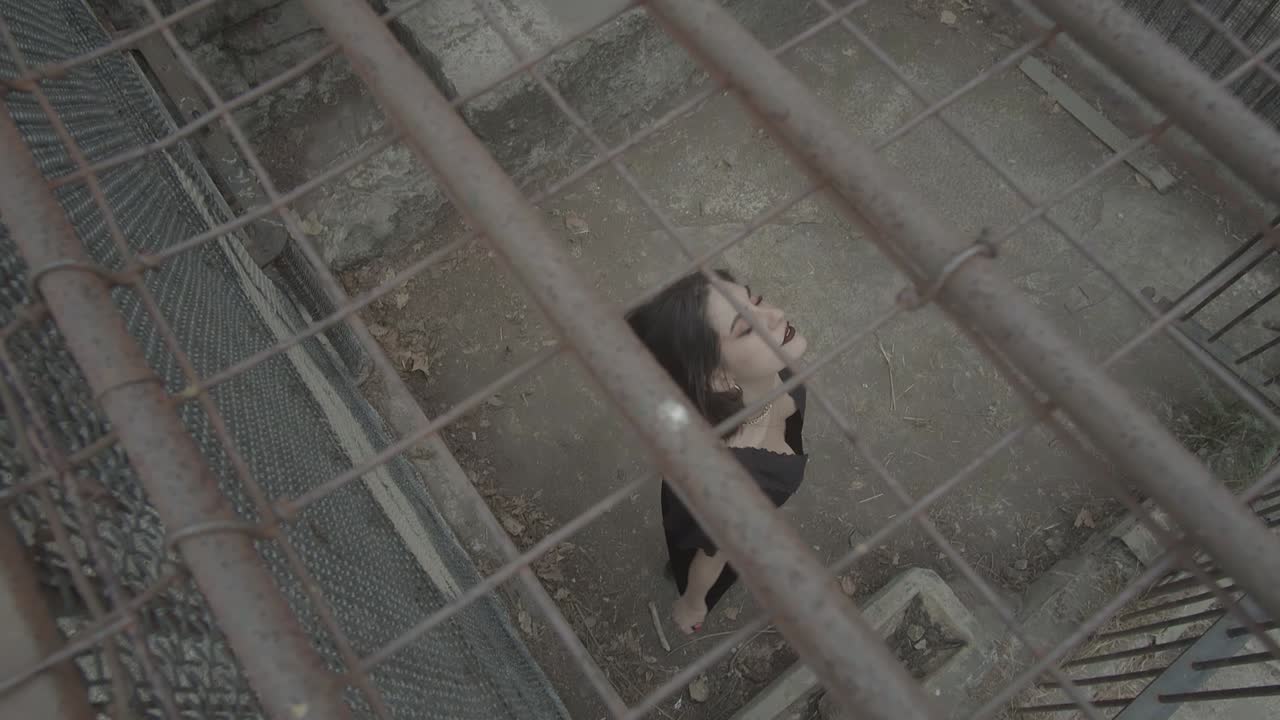 toma de arriba hacia abajo de una joven girando lentamente dentro de una jaula