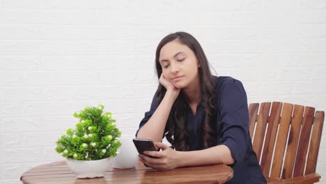 Indian-girl-scrolling-phone-at-a-cafe