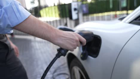 Progressive-businessman-plugs-charger-plug-from-charging-station-to-his-EV.