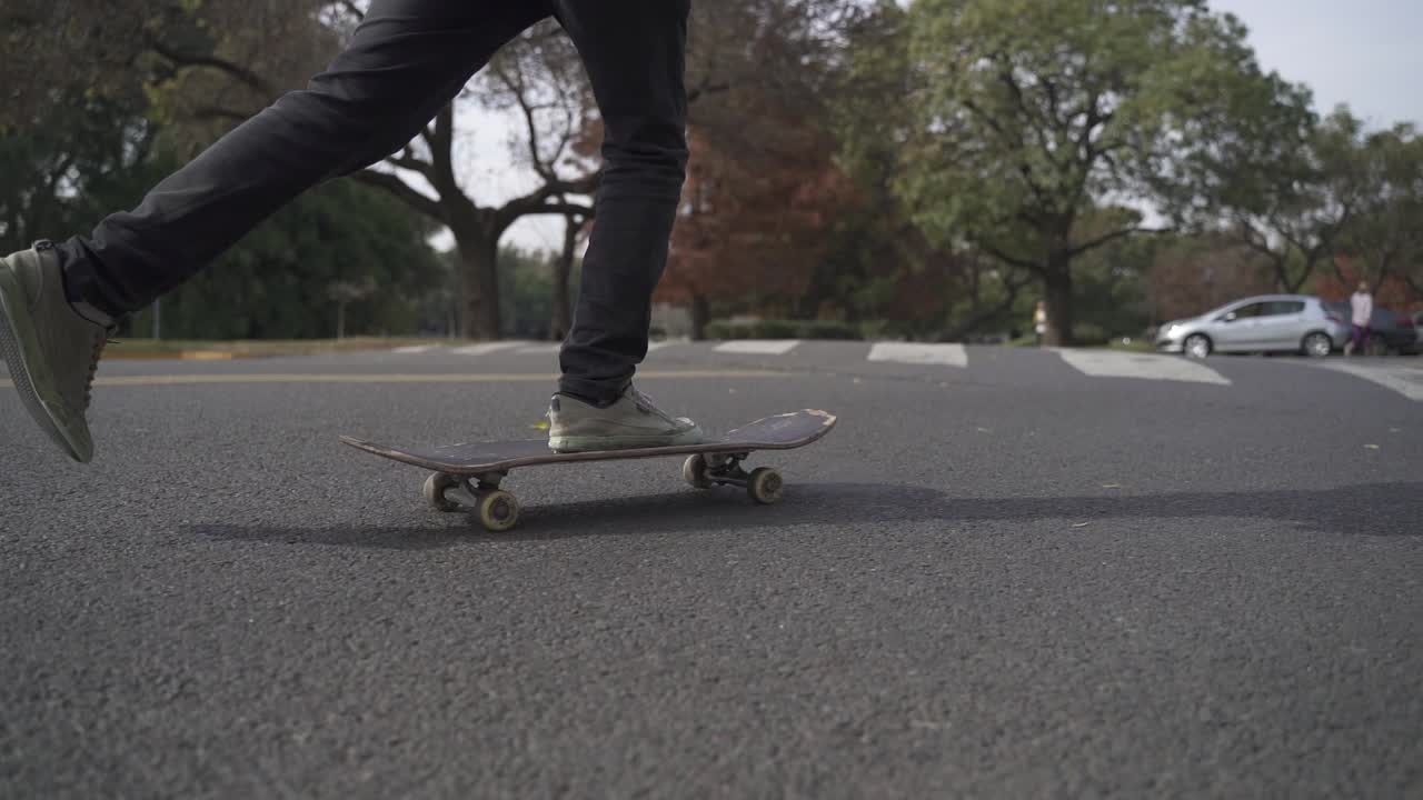 Close up of skateboard being ride on the street with park at background