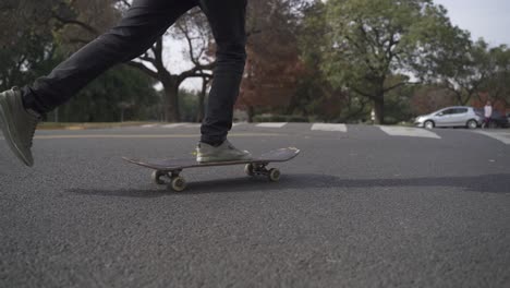 close up of skateboard being ride on the street with park at background