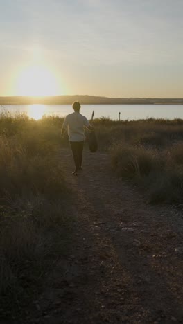 musician with guitar at sunset by the lake