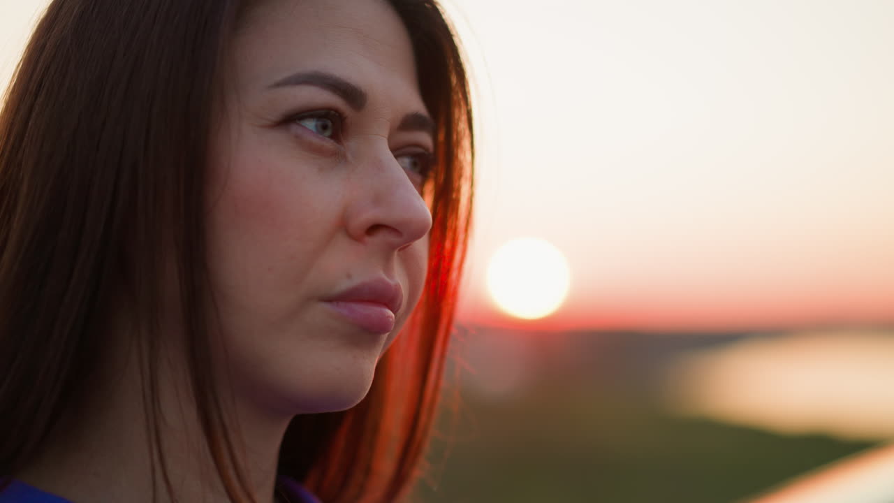 mujer molesta se encuentra contra el sol rojo de la tarde de cerca dama de cabello oscuro piensa en las dificultades de la vida