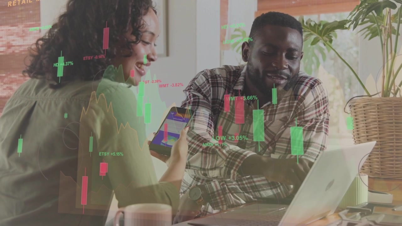 Woman showing smartphone and coworker tapping laptop at desk, animated candlesticks driving trade