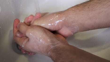 a person performing a thorough hand washing under the white sink