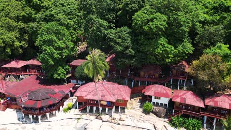 Island-Hill-Huts-in-lush-Jungle-fores,-emerald-waters-lagoon