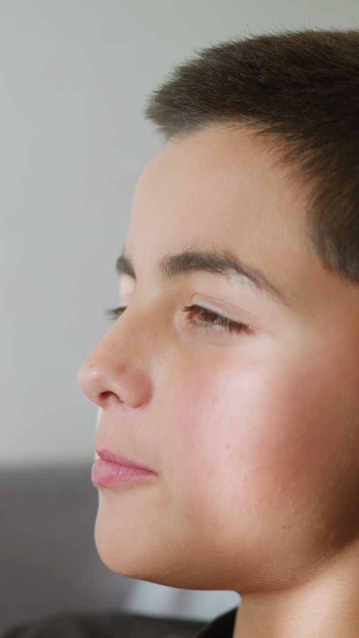 Side view of young boy eating cake, enjoying the treat with light reflecting off his face, he looks relaxed and satisfied, savoring the moment with a joyful expression