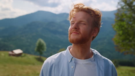 young man bearded face looking around enjoying mountains landscape close up.