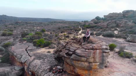 Man-sitting-on-the-rock-formation-4k