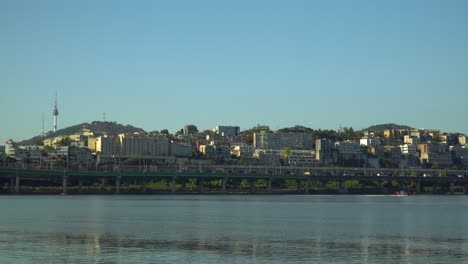 Water-Rescue-Unit-on-Red-Motorboat-Patroling-on-Han-river-with-Namsan-N-Seoul-Tower-and-Yongsan-gu-district-landscape-over-clean-sky-in-Autumn,-South-Korea