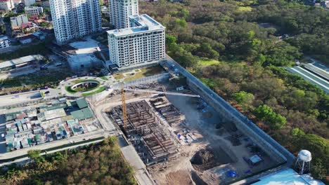 vista aérea de los terrenos del sitio de construcción y la grúa entre el paisaje urbano en desarrollo y la vegetación exuberante de alabang, ciudad de muntinlupa