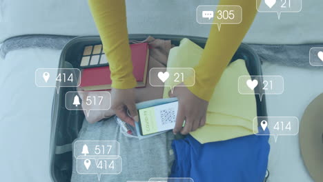 animation of media notifications over biracial woman with smartphone packing suitcase