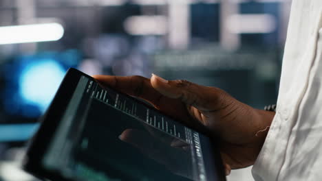 close up of data center software developer using tablet to review code