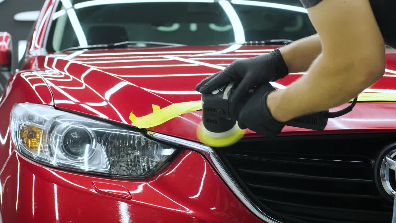 Worker polish a red car. Car detailing - Men are using machinery car polishers maintenance to remove marks repair according to the surface of the car's paint before contin