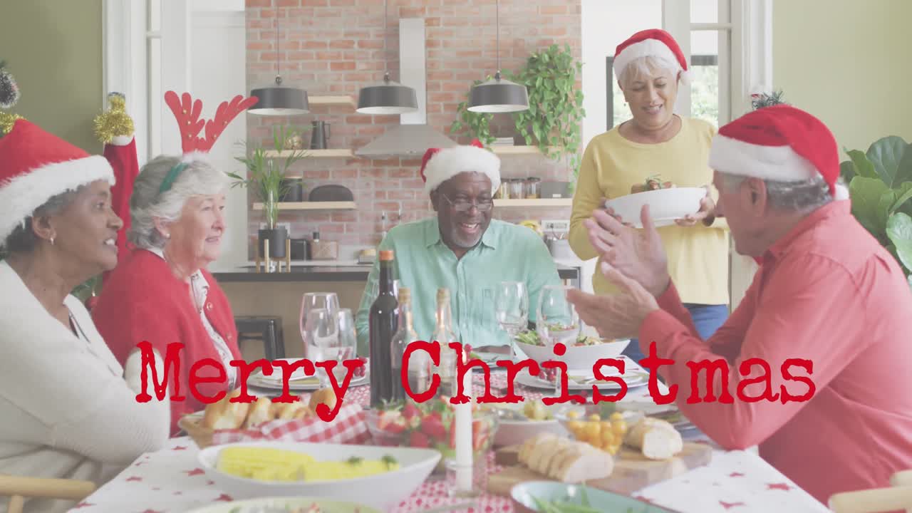 Animação de texto "Feliz Natal" sobre amigos diversos e idosos sentados à mesa no Natal