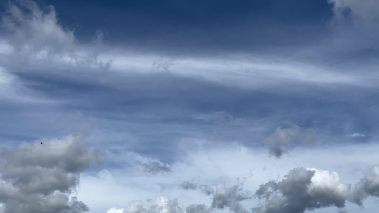 Timelapse shot of flying white and black clouds and blue sky in background,nature film