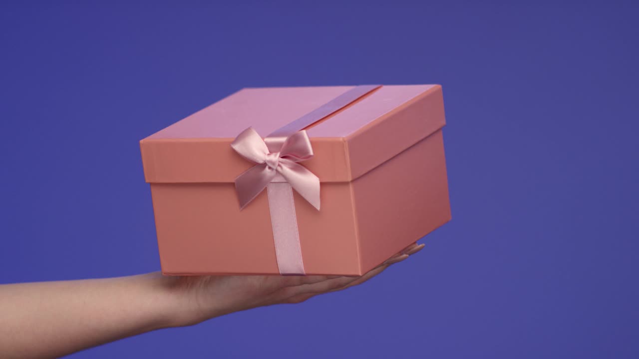 la mano de una mujer sosteniendo una hermosa caja de regalos en pantalla azul; concepto de celebración