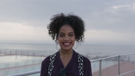 portrait-of-beautiful-hispanic-woman-with-frizzy-hair-laughing-cheerful-by-ocean-seaside