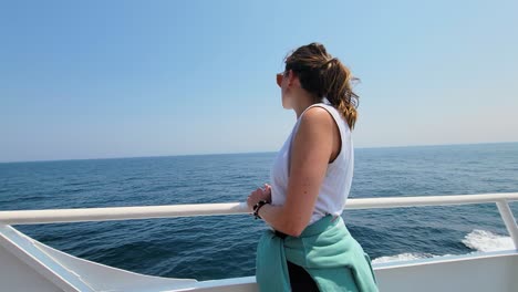 beautiful female traveler on a yacht puts on sunglasses and admire calm blue ocean on a sunny day