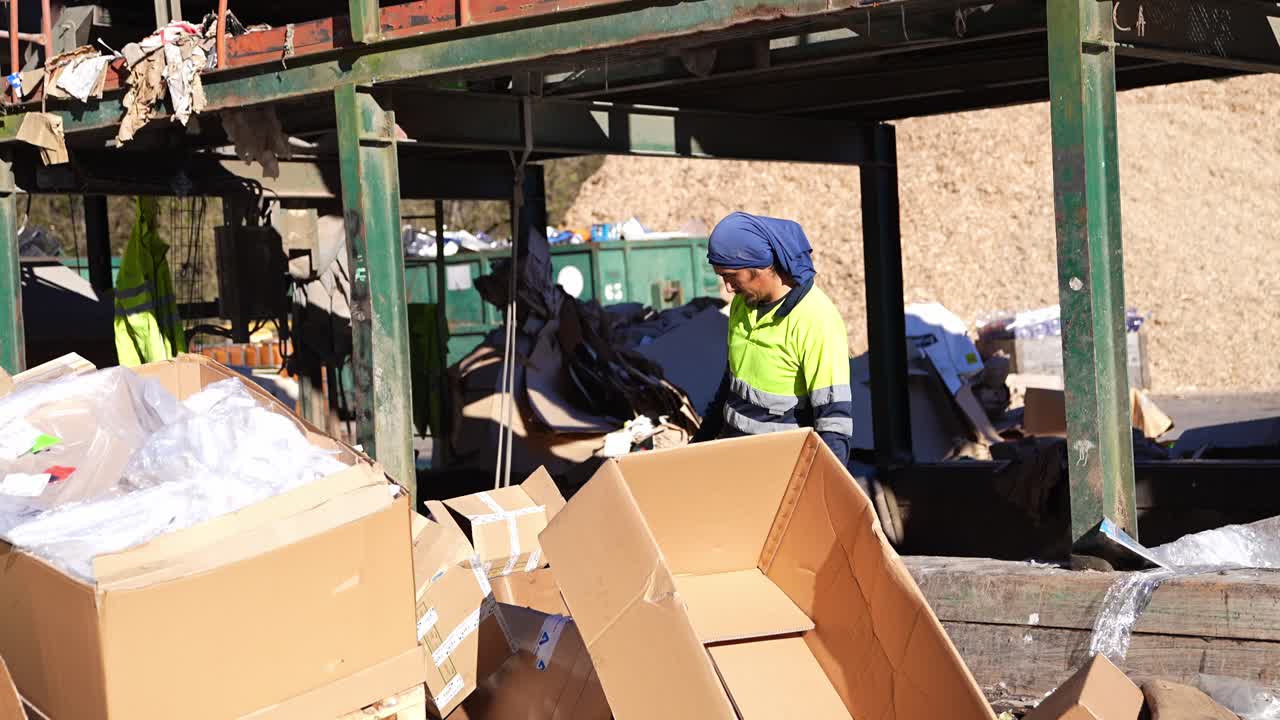 Recycling worker sorting cardboard and recyclable materials