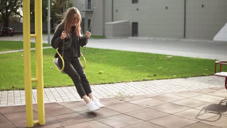 Long-haired-woman-swinging-on-a-swing-in-the-green-park-calmly