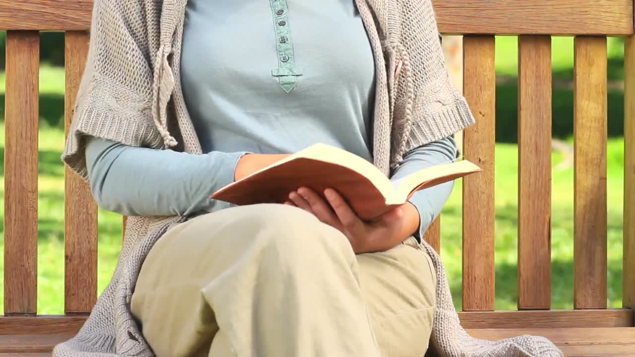 Young woman reading a book on a bench