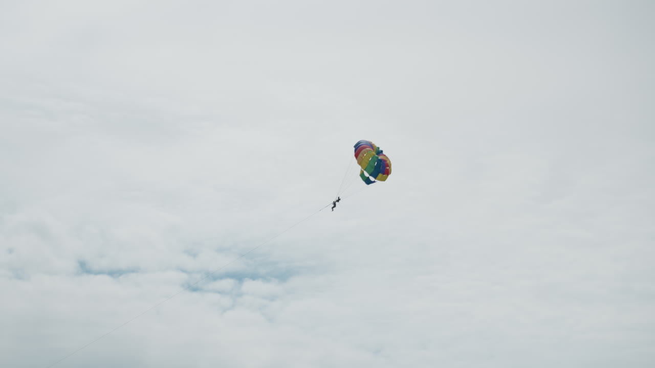 Solo fly above calm waters. Vivid aerial journey over serene seascape with colorful parachute. Lively sky adventure featuring solo parasail drifting peacefully over tranquil ocean scenery